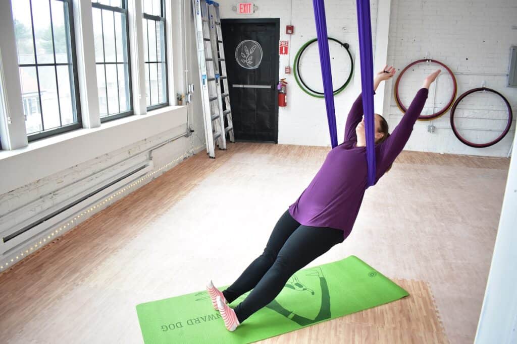 A woman in mountain pose at an aerial yoga studio in Hudson.