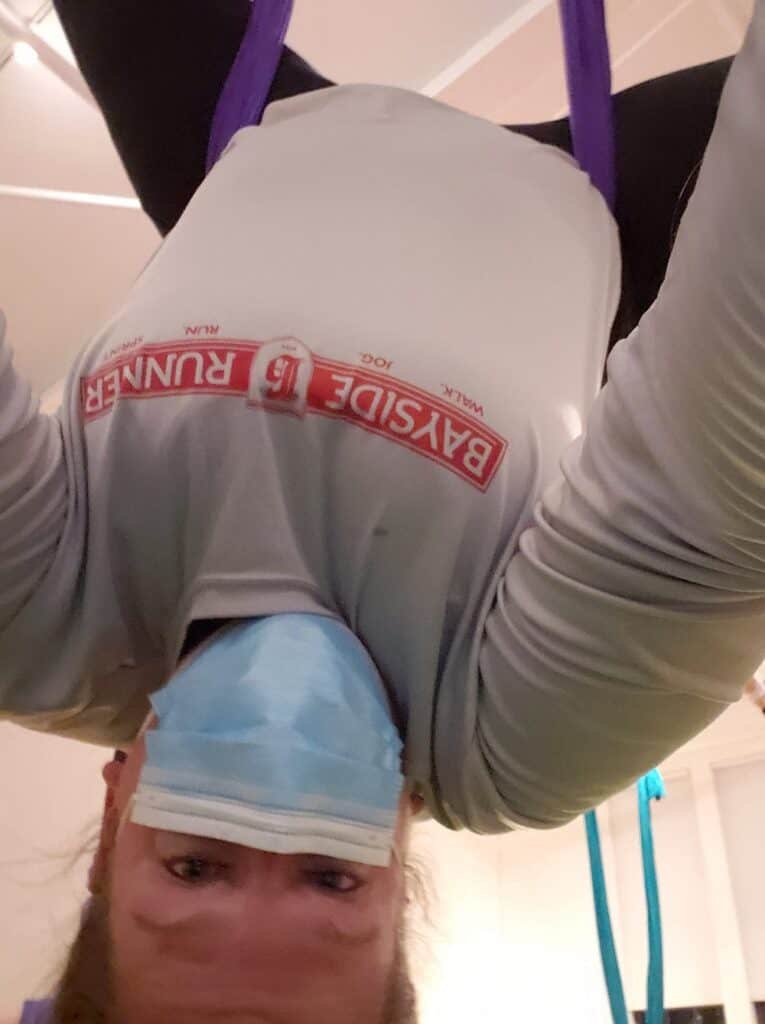 A woman upside down at an aerial yoga class.